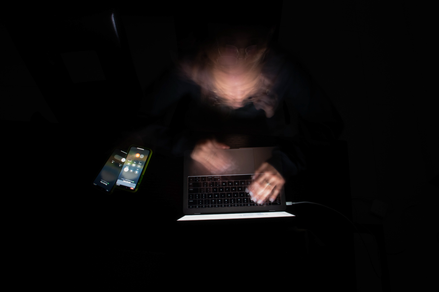 photo of blurred face and hands at a laptop computer